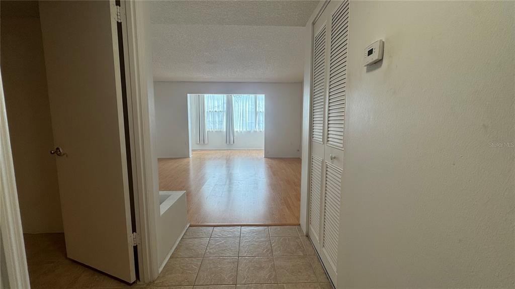 A tiled entryway leads into a living area with light wood flooring and large windows — 1900 68TH STREET N UNIT 106, ST PETERSBURG, FL