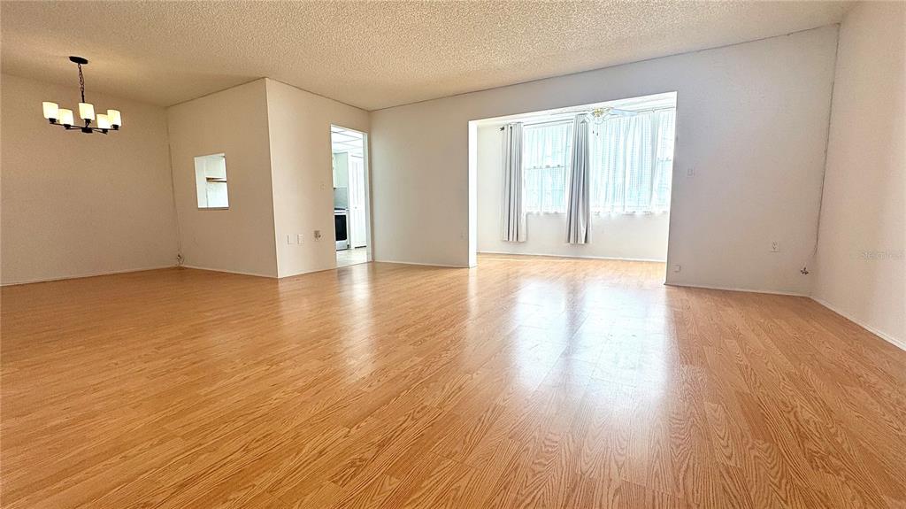 A spacious living room features light wood-look flooring, white walls, and a large window — 1900 68TH STREET N UNIT 106, ST PETERSBURG, FL
