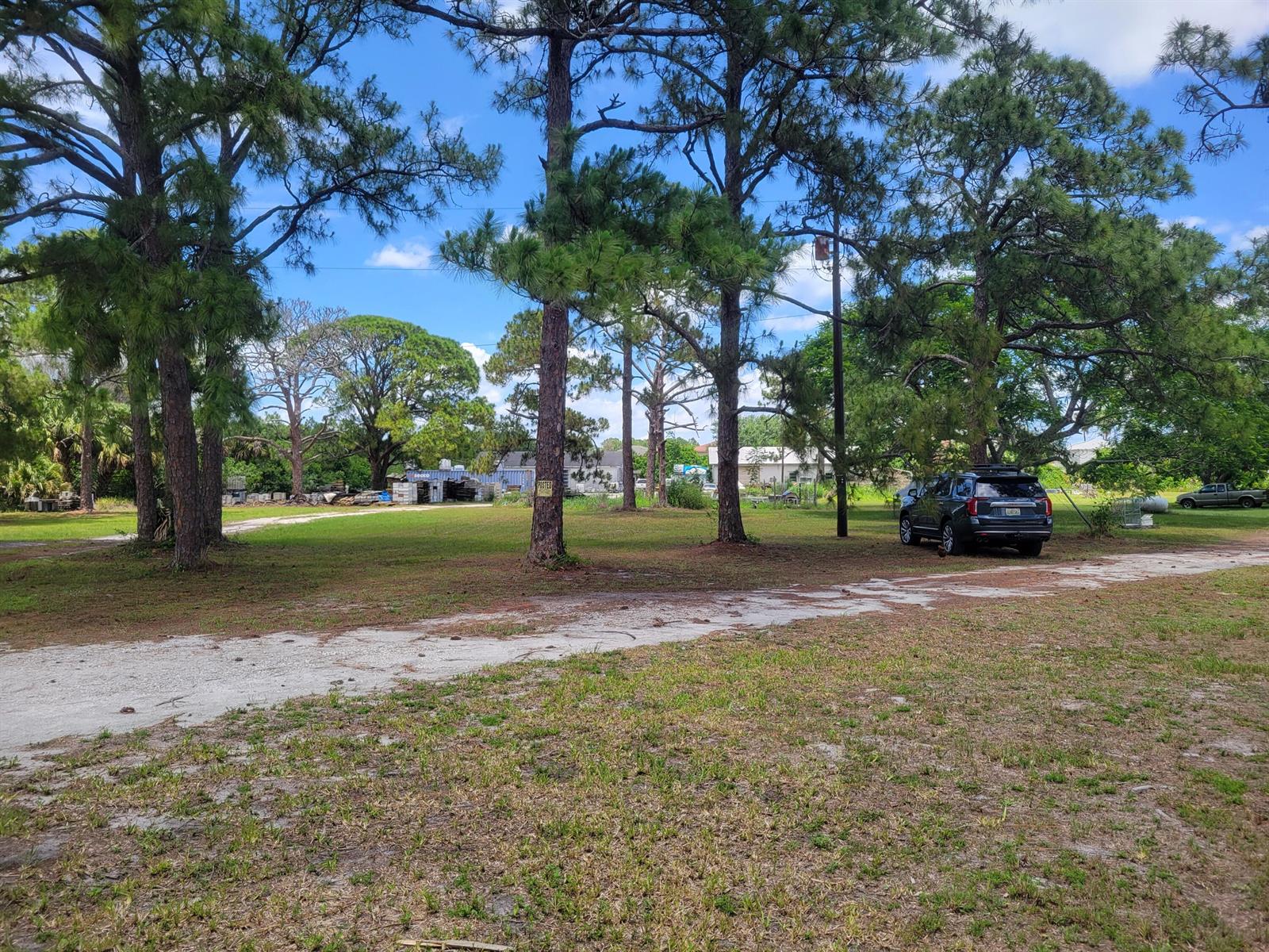 A grassy lot with several tall pine trees and a parked SUV in the background — 9610 Orange Avenue, Fort Pierce FL 34945, FORT PIERCE, FL