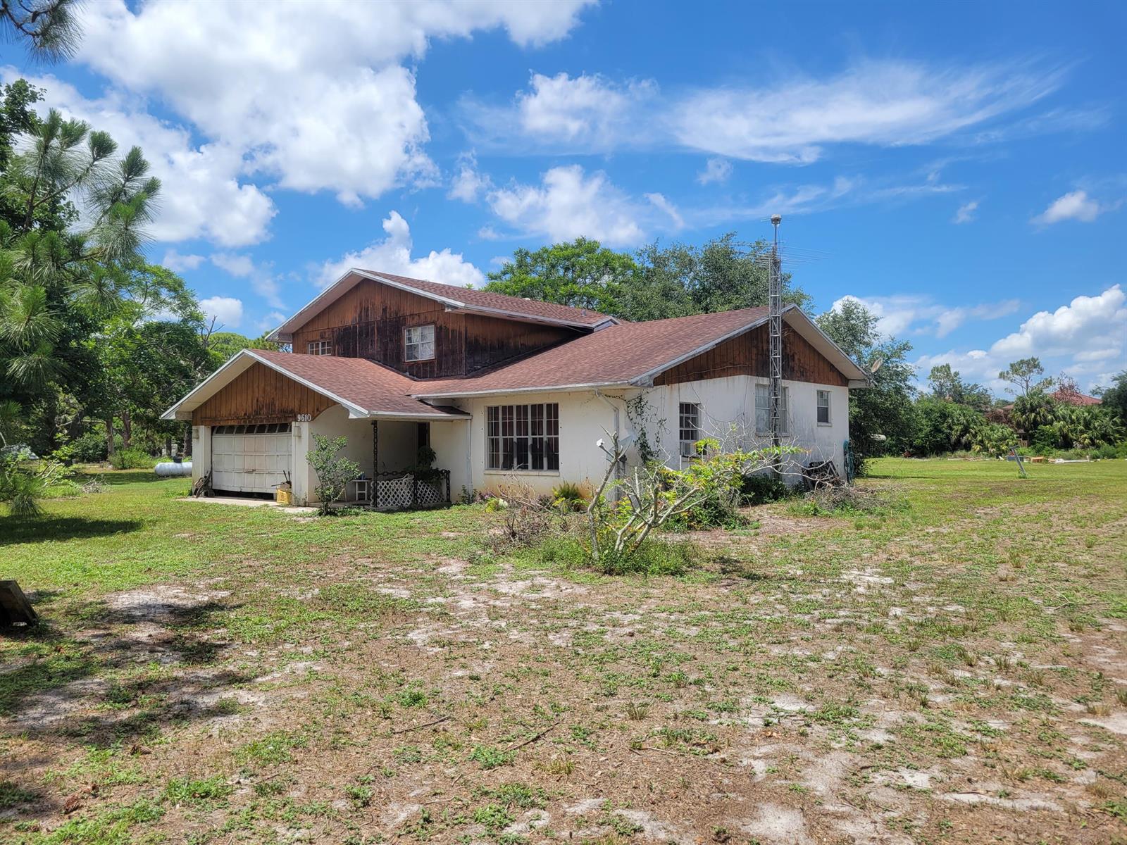 A two-story house with a garage, wood siding, and a large antenna in a yard — 9610 Orange Avenue, Fort Pierce FL 34945, FORT PIERCE, FL