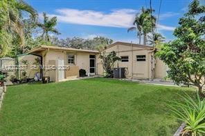 A backyard view of a single-story house with a lawn, palm trees, and a shed — 2199 NE 182nd St # 1, North Miami Beach FL 33162, NORTH MIAMI BEACH, FL