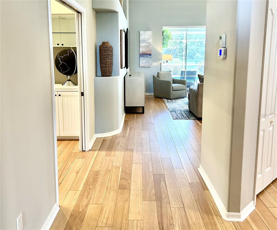 A hallway with wood flooring leads into a living room with a view of a pool — 8918 OLDE HICKORY AVENUE, SARASOTA, FL