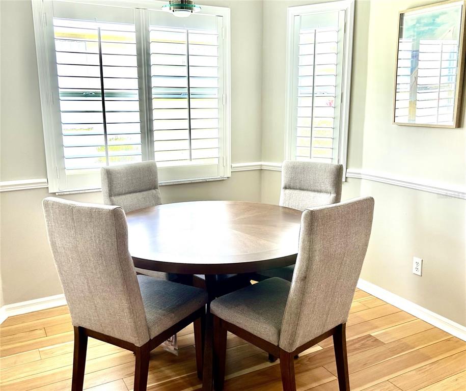 A dining area features a round wooden table, four upholstered chairs, and white plantation shutters — 8918 OLDE HICKORY AVENUE, SARASOTA, FL