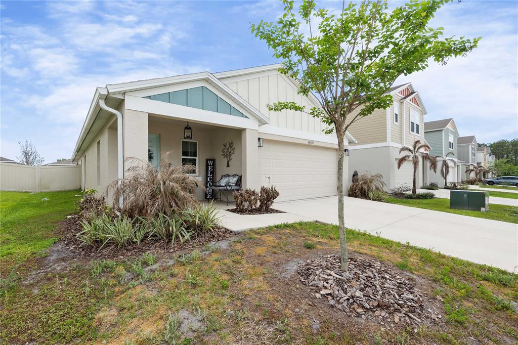 A single-story house with a beige stucco exterior, a two-car garage, and a covered porch — 34102 SCARLET SAGE COURT, WESLEY CHAPEL, FL