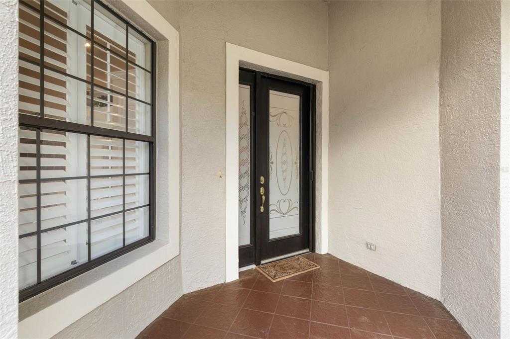 A covered entryway features a dark brown front door with glass panels and tiled flooring — 10 RIVER PARK DRIVE N, PALM COAST, FL