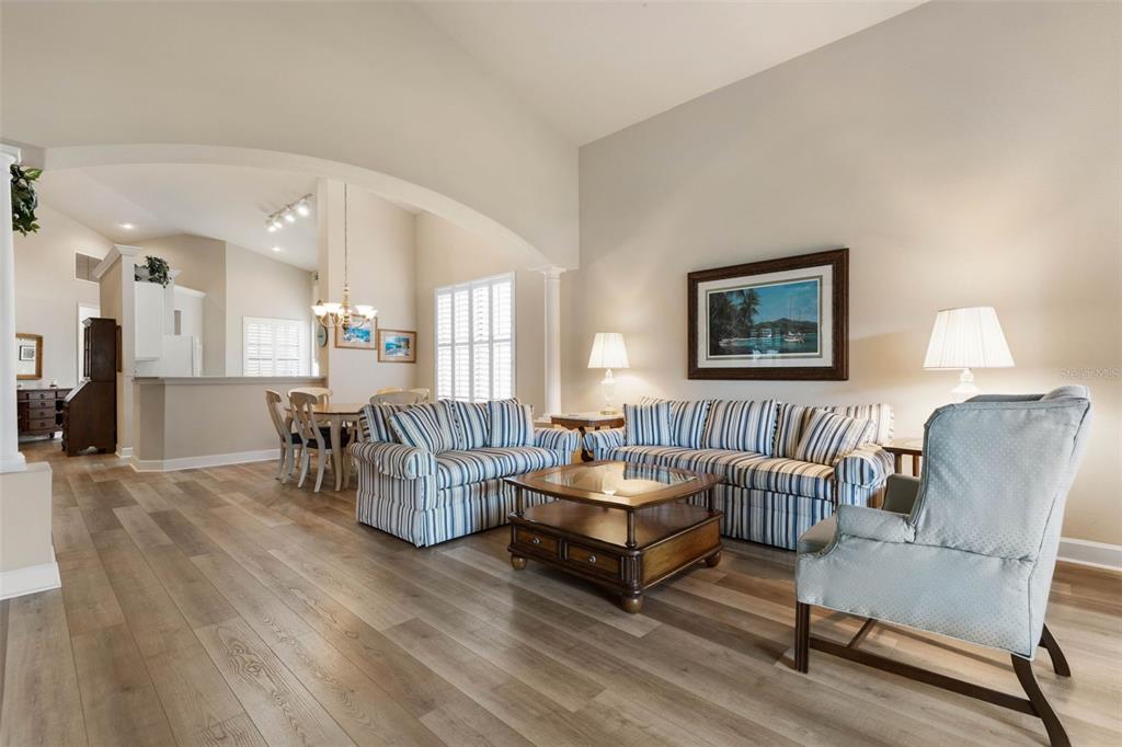 A living room with striped sofas, a coffee table, and light wood-look flooring — 10 RIVER PARK DRIVE N, PALM COAST, FL