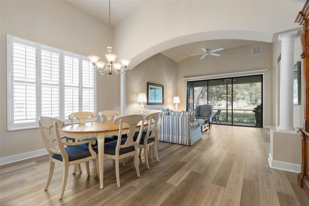 A dining area with a wooden table and chairs opens into a living room with sliders — 10 RIVER PARK DRIVE N, PALM COAST, FL