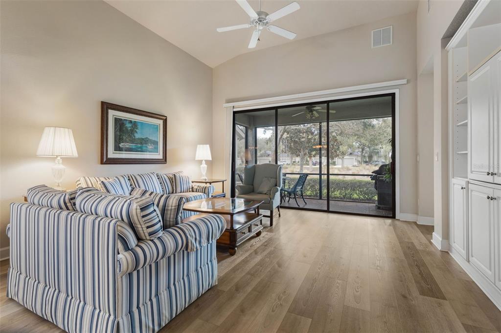 A living room with striped furniture, wood flooring, and a sliding glass door to a patio — 10 RIVER PARK DRIVE N, PALM COAST, FL