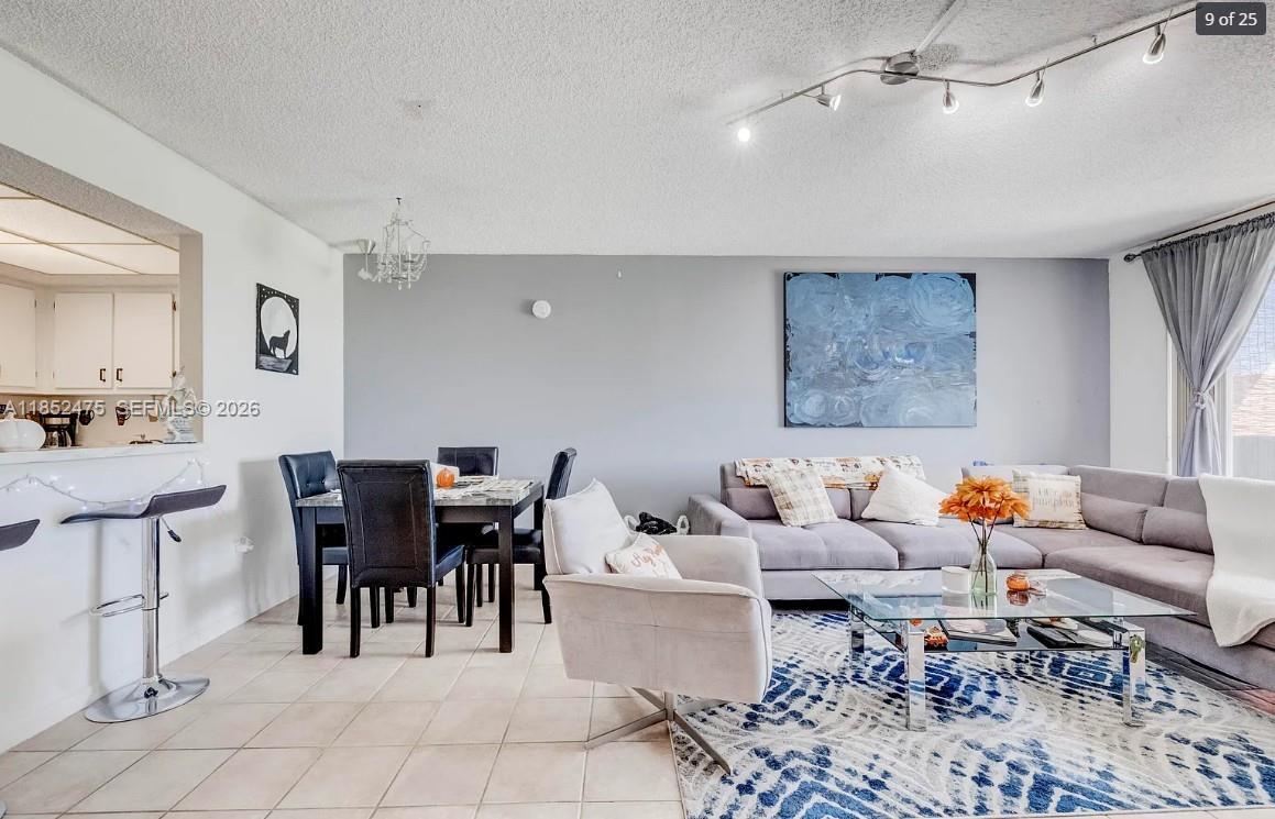 An open-concept living and dining area features tile flooring, a gray sectional sofa, and track lighting — 5570 NW 44th St # 412A, Lauderhill FL 33319, LAUDERHILL, FL