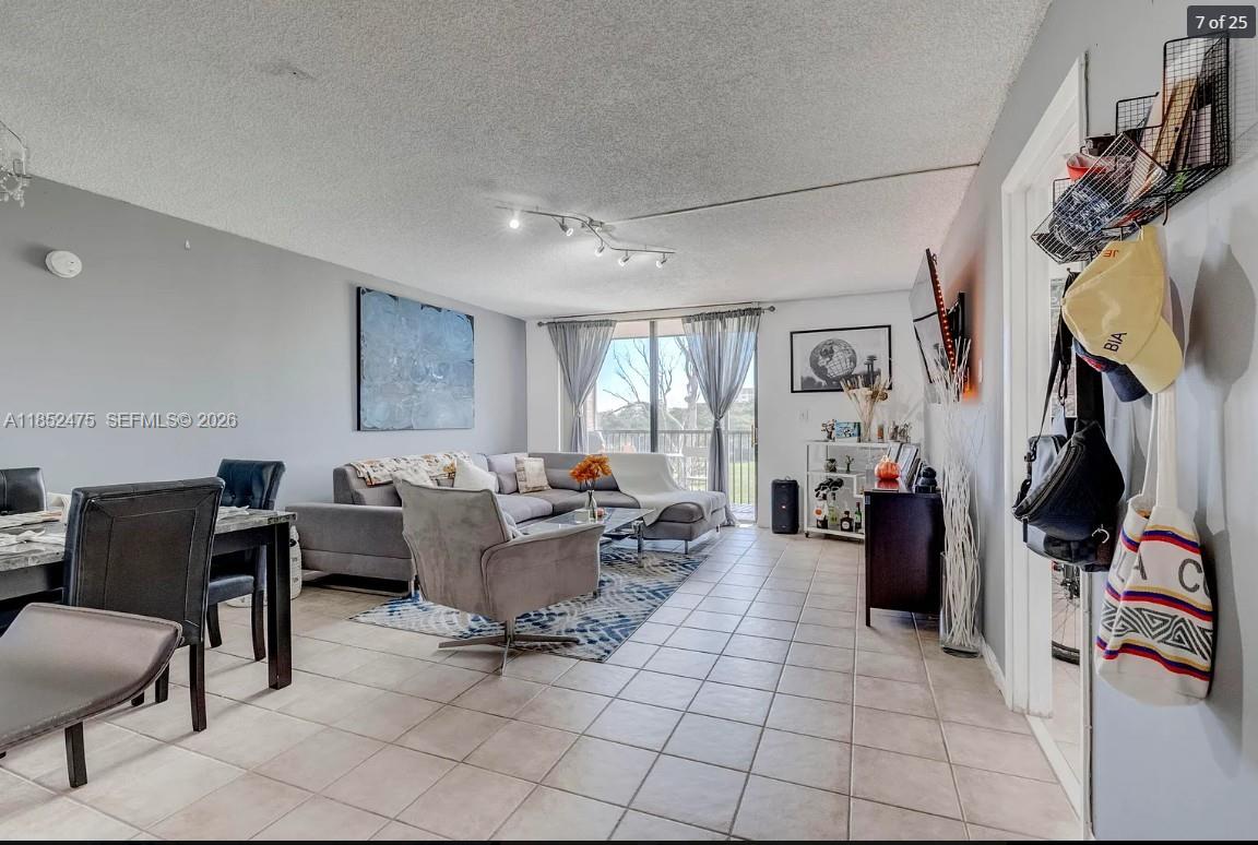 A living room features tile flooring, a gray sectional sofa, and a sliding glass door — 5570 NW 44th St # 412A, Lauderhill FL 33319, LAUDERHILL, FL