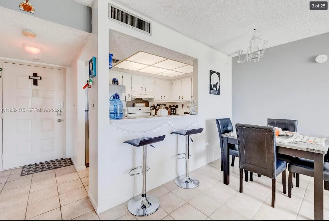 A dining area with a breakfast bar, stools, and a view into the kitchen — 5570 NW 44th St # 412A, Lauderhill FL 33319, LAUDERHILL, FL