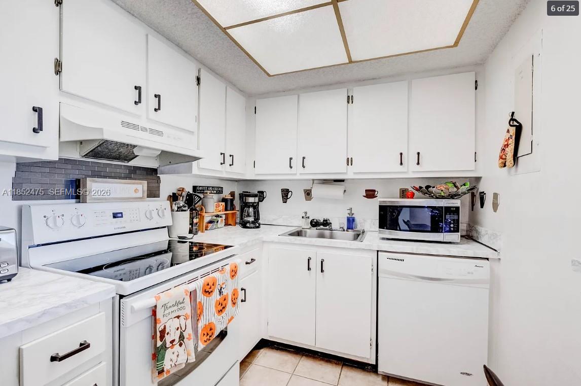 A kitchen with white cabinets, white appliances, a tiled backsplash, and a drop ceiling — 5570 NW 44th St # 412A, Lauderhill FL 33319, LAUDERHILL, FL