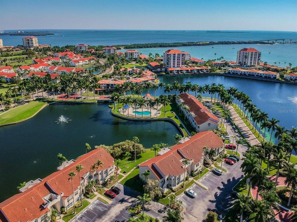 An aerial view of a waterfront residential complex with red-roofed buildings, palm trees, and pools — 6291 BAHIA DEL MAR CIRCLE UNIT 903, ST PETERSBURG, FL