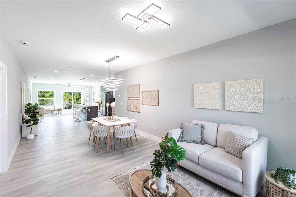 An open-concept living and dining area features light wood-look flooring and modern light fixtures — 14350 MARLIN AVENUE, PORT CHARLOTTE, FL