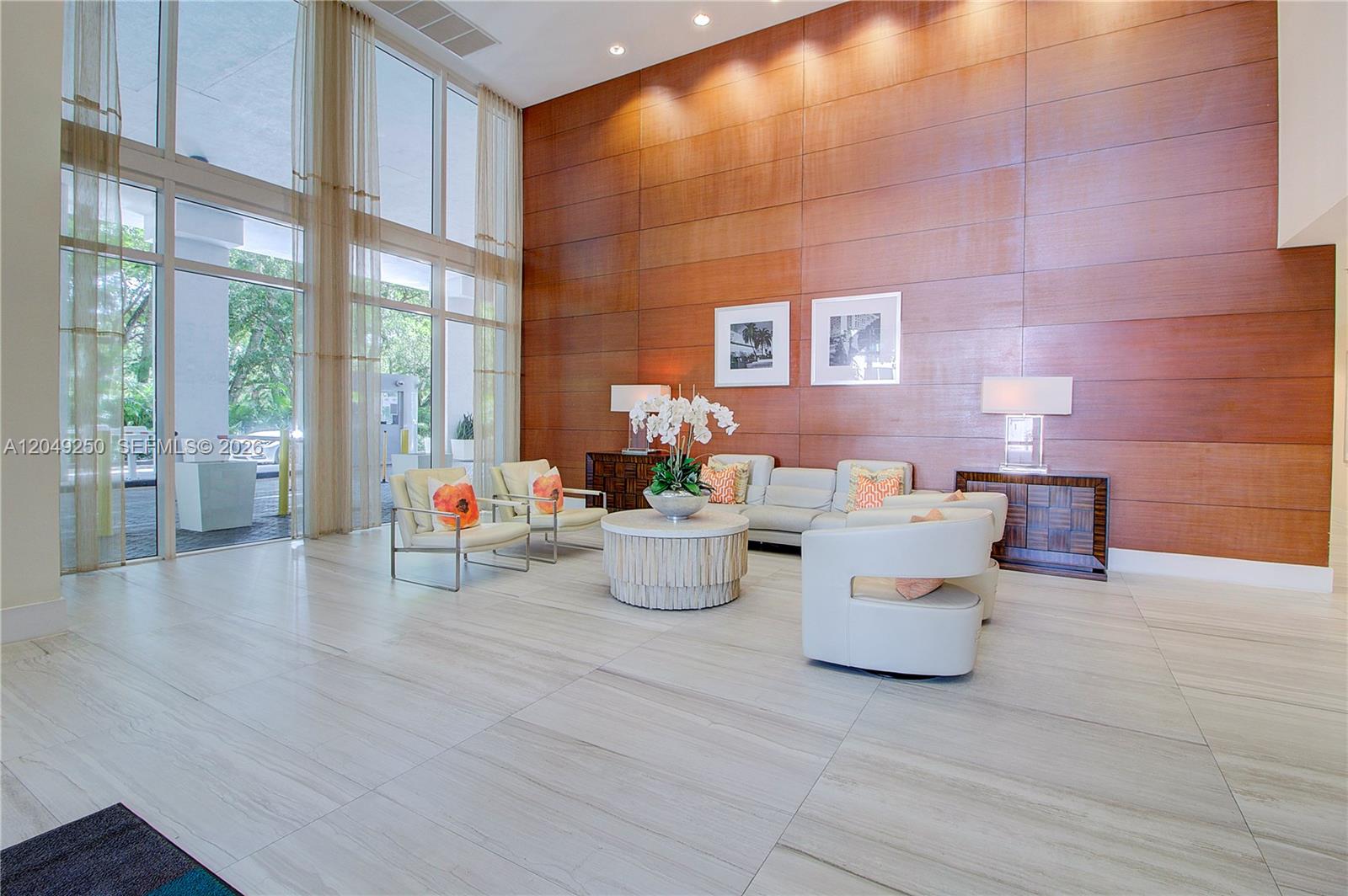 A modern lobby features floor-to-ceiling windows, wood-paneled walls, and light-colored tile flooring — 1871 NW S River Dr # 1804, Miami FL 33125, MIAMI, FL