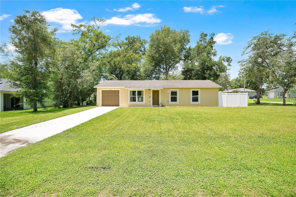 A single-story house with a tan exterior, a one-car garage, and a large front lawn — 1345 GRAND AVENUE, ORANGE CITY, FL