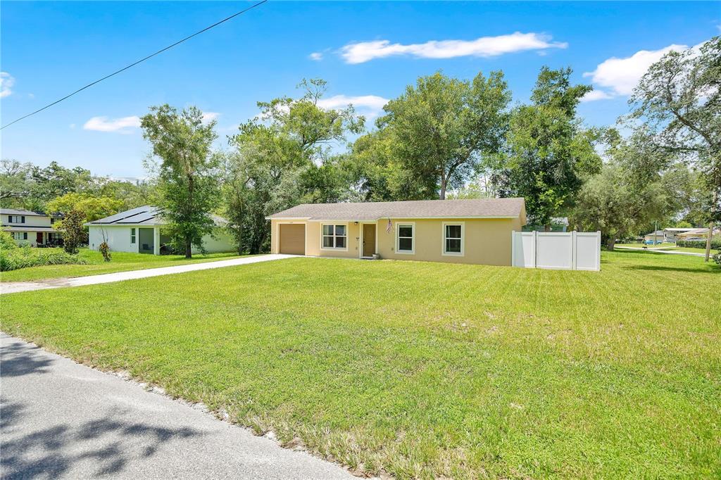 A single-story, light yellow house with a garage and a large front lawn — 1345 GRAND AVENUE, ORANGE CITY, FL