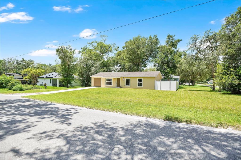 A single-story yellow house with a garage sits on a large, grassy lot — 1345 GRAND AVENUE, ORANGE CITY, FL