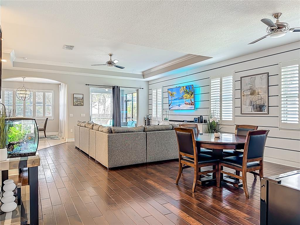 A living and dining area features dark wood floors, a sectional sofa, and shiplap walls — 6506 NESTALL COURT, APOLLO BEACH, FL