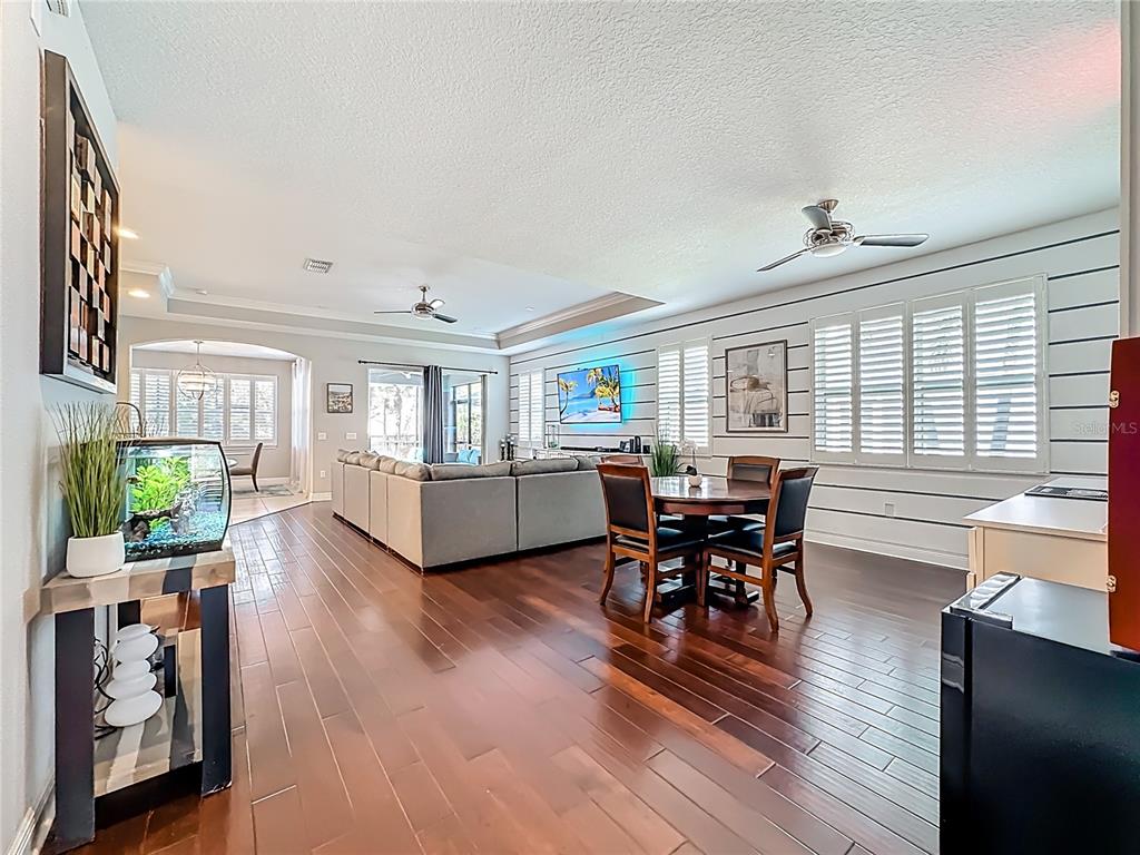 An open-concept living and dining area features dark hardwood floors and horizontal wall paneling — 6506 NESTALL COURT, APOLLO BEACH, FL