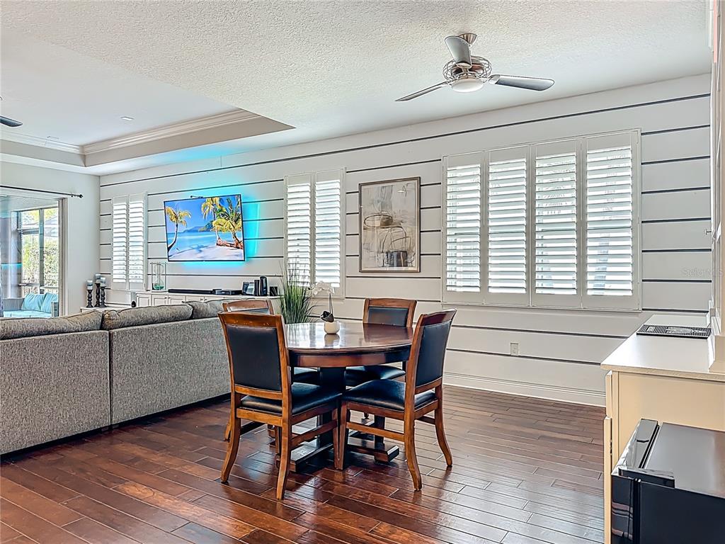 A dining area with a round wooden table, chairs, and shiplap walls near a living room — 6506 NESTALL COURT, APOLLO BEACH, FL
