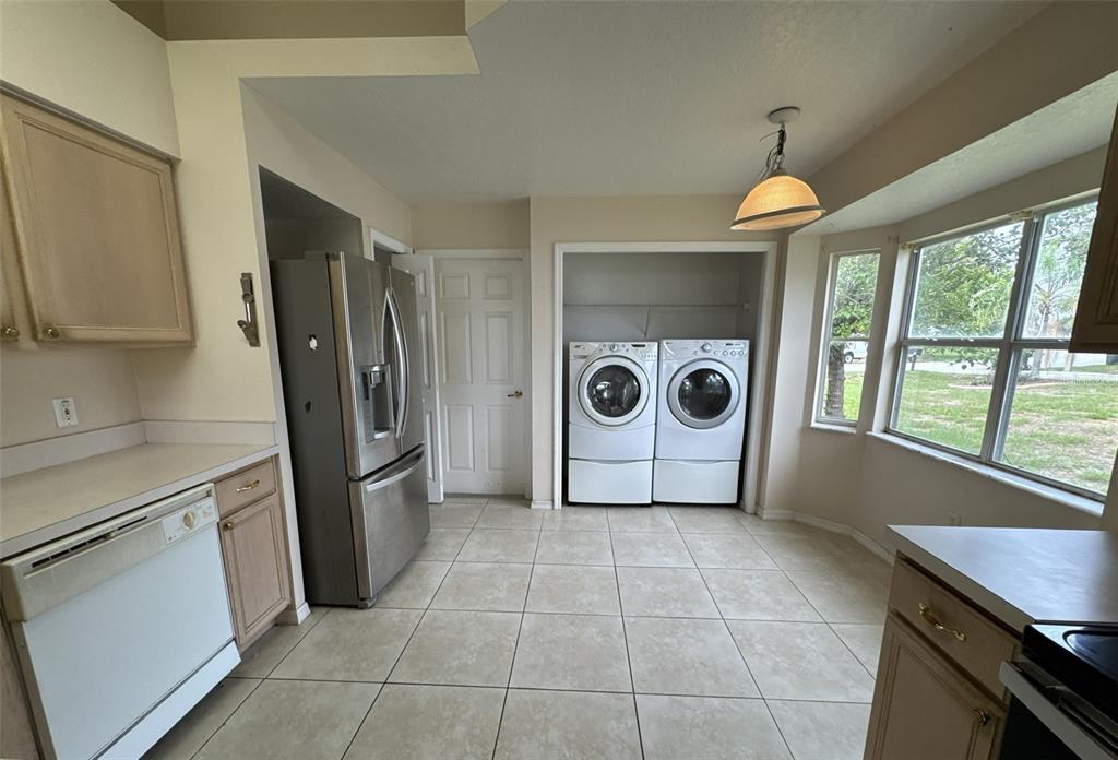 A kitchen with tile floors, stainless steel appliances, and a laundry nook with stacked machines — 357 THORNBUSH PARKWAY, DAVENPORT, FL