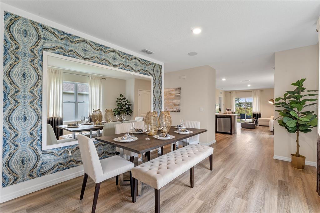 A dining room features a large mirror, patterned wallpaper, a wooden table, and a bench — 3011 GREY MOSS DRIVE, ST CLOUD, FL