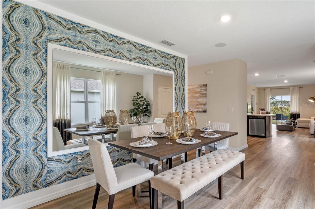 A dining room features a wooden table, upholstered chairs, a tufted bench, and patterned wallpaper — 3011 GREY MOSS DRIVE, ST CLOUD, FL