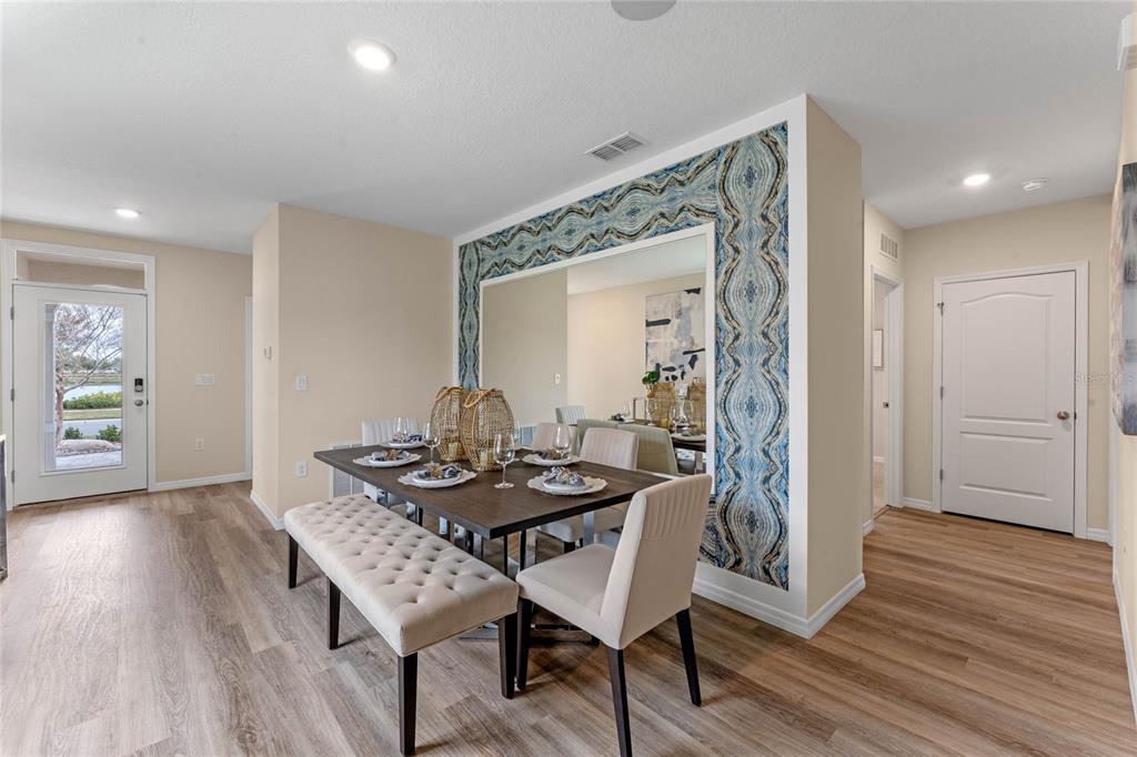A dining room features a dark wood table, a tufted bench, and a decorative wallpaper accent — 3011 GREY MOSS DRIVE, ST CLOUD, FL