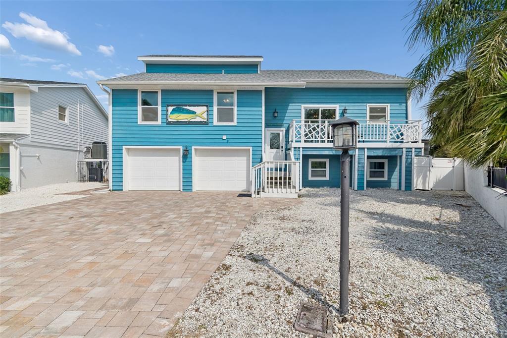 A two-story blue house with a two-car garage, a balcony, and a paved driveway — 330 6TH AVENUE, INDIAN ROCKS BEACH, FL