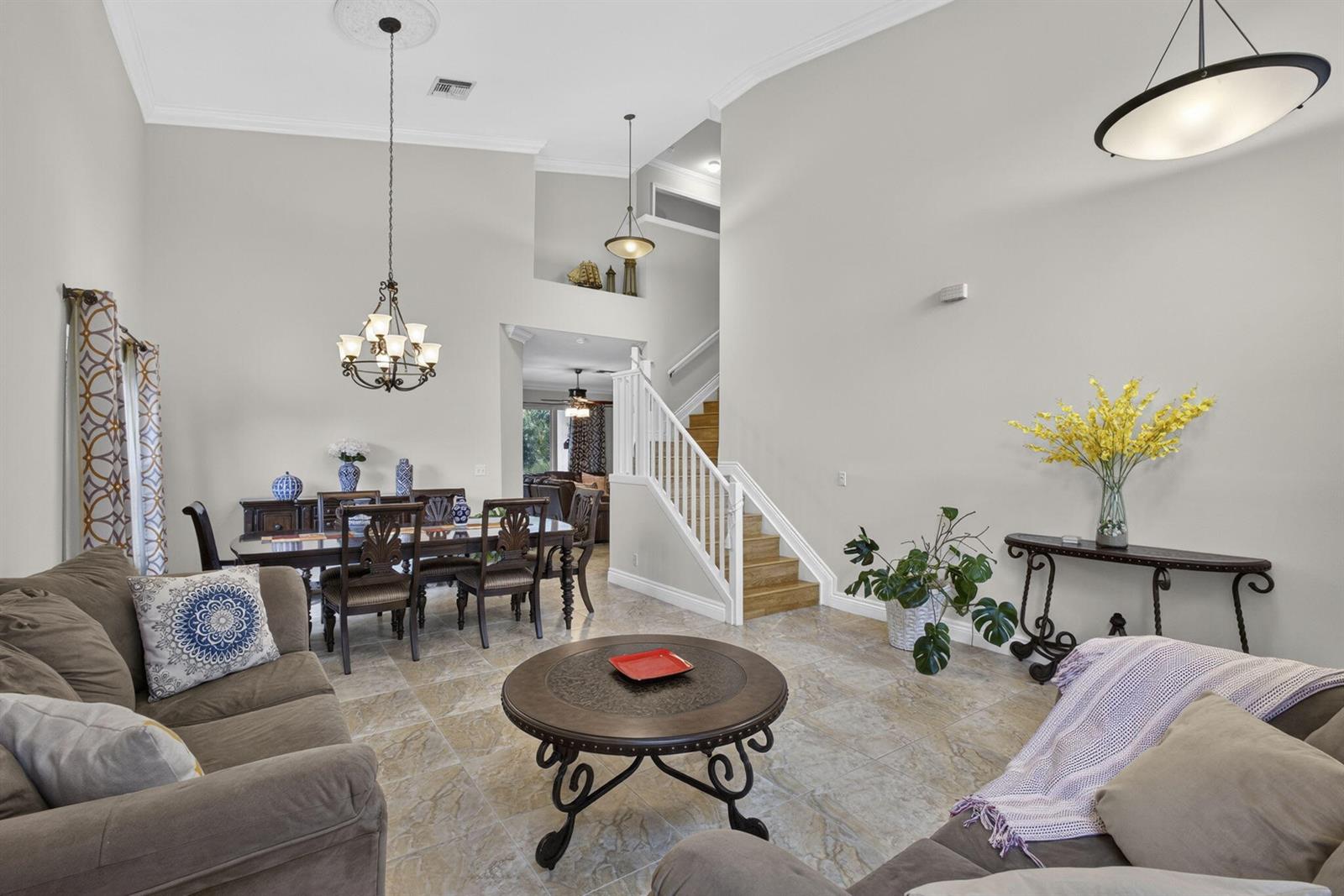 A living and dining area features tile floors, a staircase, and high ceilings with chandeliers — 11483 Beacon Pointe Lane, Wellington FL 33414, WELLINGTON, FL