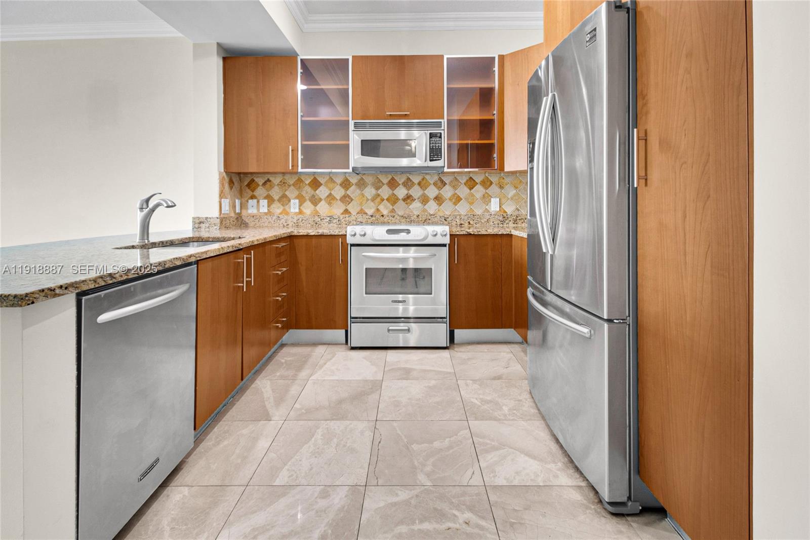 A kitchen features wood cabinets, stainless steel appliances, granite countertops, and light tile flooring — 1945 S Ocean Dr # 1410, Hallandale Beach FL 33009, HALLANDALE BEACH, FL