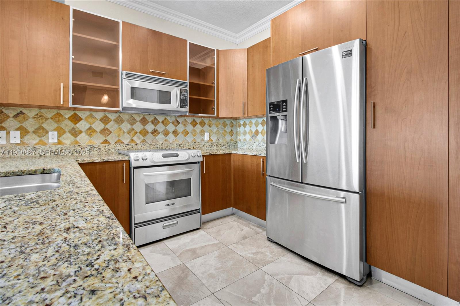 A kitchen features wood cabinets, granite countertops, stainless steel appliances, and a tiled backsplash — 1945 S Ocean Dr # 1410, Hallandale Beach FL 33009, HALLANDALE BEACH, FL