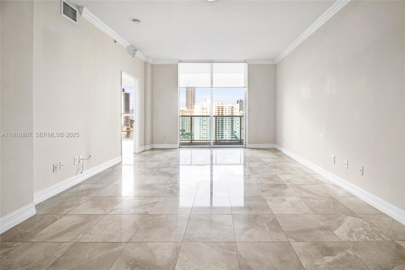 An empty room features large light-colored floor tiles, white walls, and a balcony with city views — 1945 S Ocean Dr # 1410, Hallandale Beach FL 33009, HALLANDALE BEACH, FL