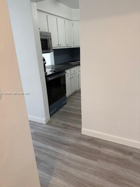 A kitchen with white cabinets, stainless steel appliances, and light-colored wood-look flooring — 1400 NE 191st St # 308, Miami FL 33179, MIAMI, FL