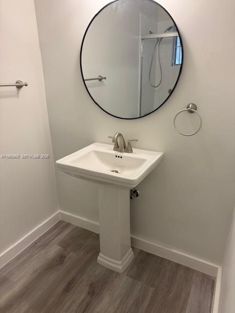 A bathroom features a pedestal sink, a round mirror, and wood-look flooring — 1400 NE 191st St # 308, Miami FL 33179, MIAMI, FL