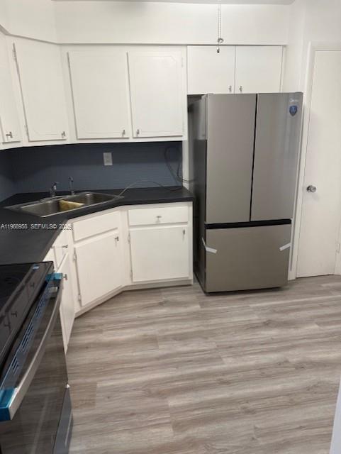 A kitchen features white cabinets, a stainless steel refrigerator, dark countertops, and light wood flooring — 1400 NE 191st St # 308, Miami FL 33179, MIAMI, FL