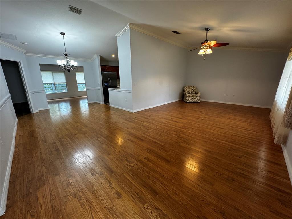 An open-concept living and dining area features light-colored walls, wood flooring, and a ceiling fan — 17522 SE 95TH CIRCLE, SUMMERFIELD, FL