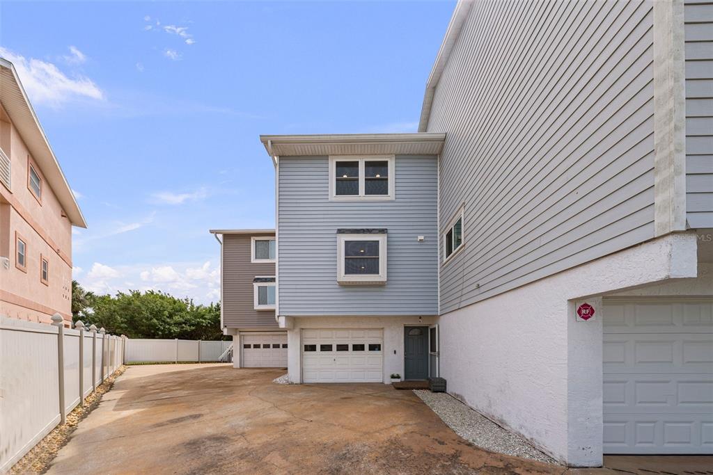 The exterior view shows a multi-story house with light blue siding, multiple garage doors, and a driveway — 619 2ND STREET UNIT 2, INDIAN ROCKS BEACH, FL