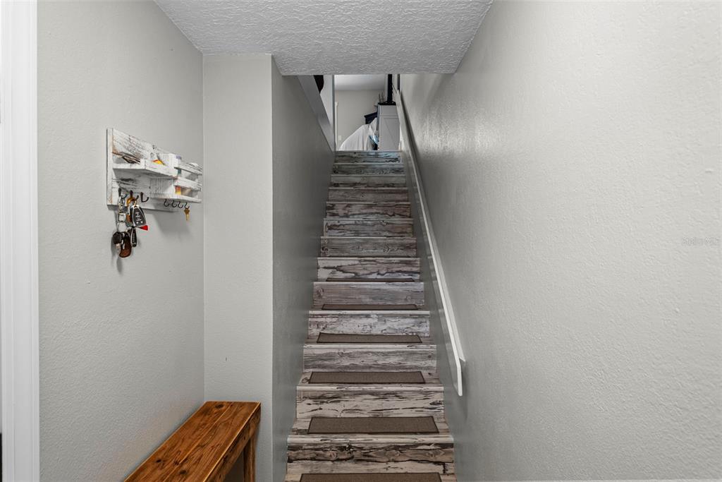A staircase with wood-look treads and carpet runners leads upward between two gray walls — 619 2ND STREET UNIT 2, INDIAN ROCKS BEACH, FL