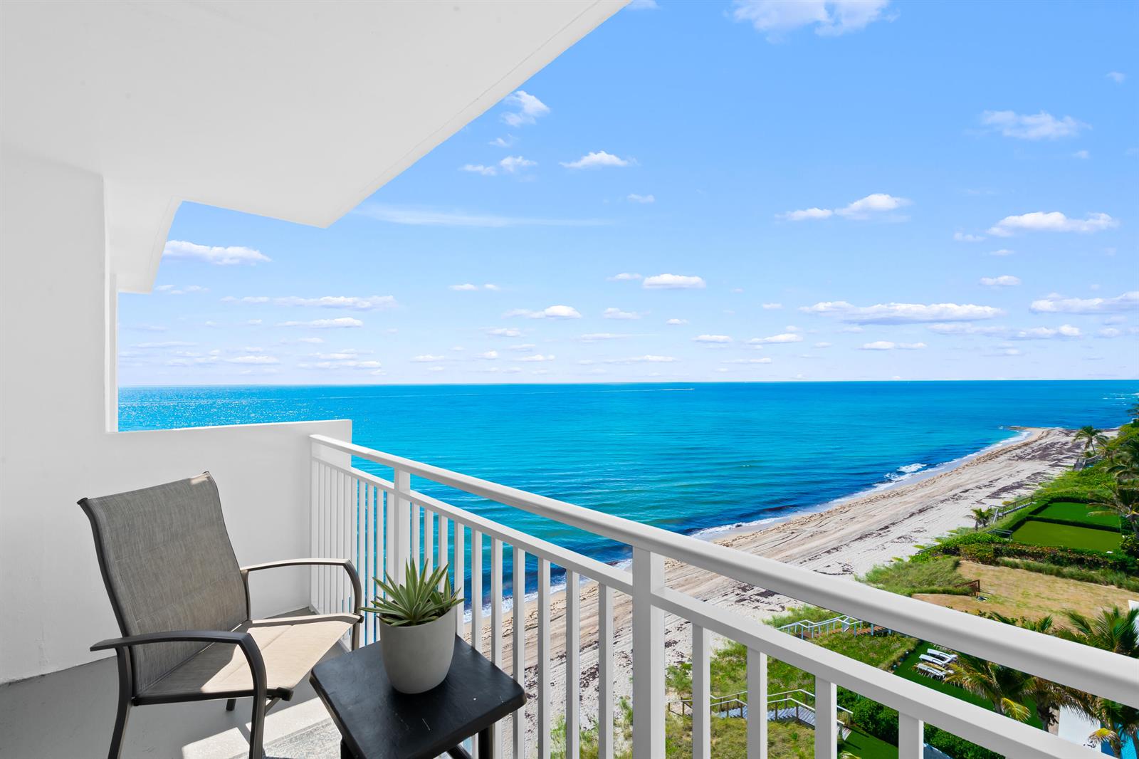 A balcony with a chair and small table overlooks a sandy beach and the ocean — 4511 S Ocean Boulevard # 807, Highland Beach FL 33487, HIGHLAND BEACH, FL
