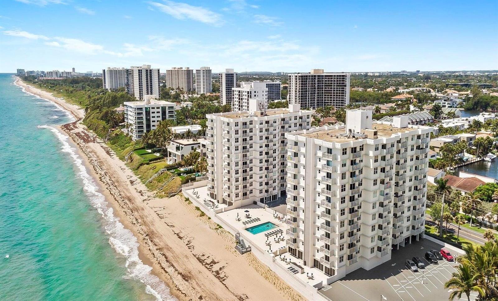 An aerial view of a white beachfront condominium complex with a pool and parking lot — 4511 S Ocean Boulevard # 807, Highland Beach FL 33487, HIGHLAND BEACH, FL