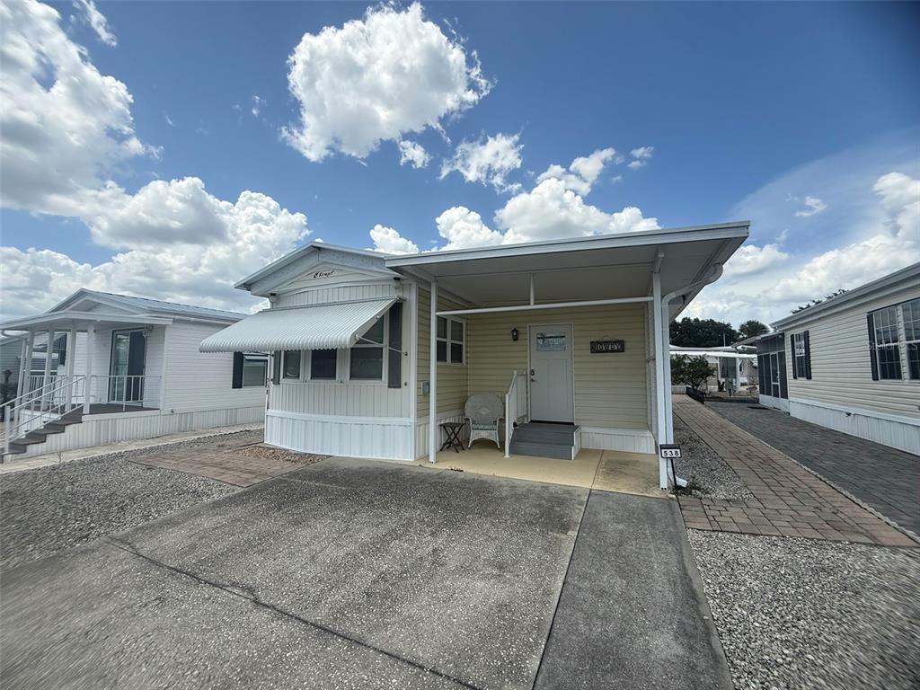 A light yellow manufactured home features a covered porch, concrete driveway, and white trim — 538 CENTER CREST BOULEVARD, DAVENPORT, FL