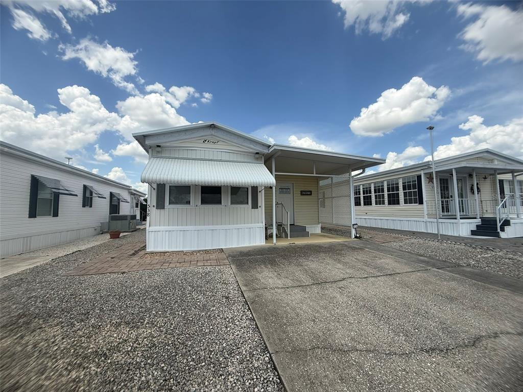 A single-story manufactured home with a white exterior, metal awning, and attached carport — 538 CENTER CREST BOULEVARD, DAVENPORT, FL