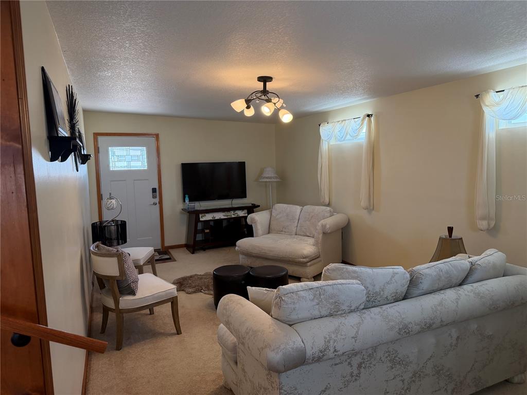 A living room features beige carpet, light-colored walls, a white sofa, and a television stand — 538 CENTER CREST BOULEVARD, DAVENPORT, FL