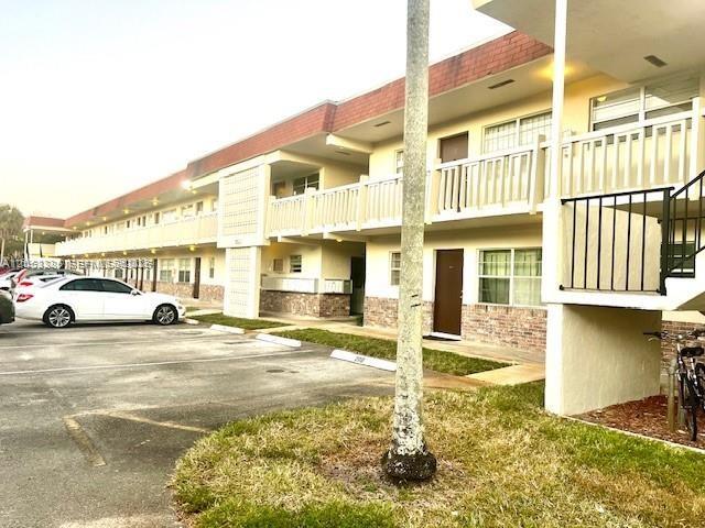 A multi-story apartment building features exterior walkways, balconies, and a parking lot with cars — 4165 SW 67th Ave # 206B, Davie FL 33314, DAVIE, FL