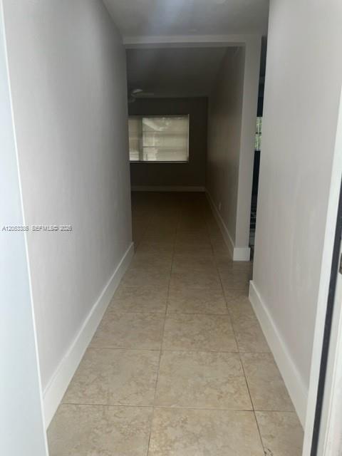 A hallway with light-colored tile flooring leads toward a room with a window — 4165 SW 67th Ave # 206B, Davie FL 33314, DAVIE, FL