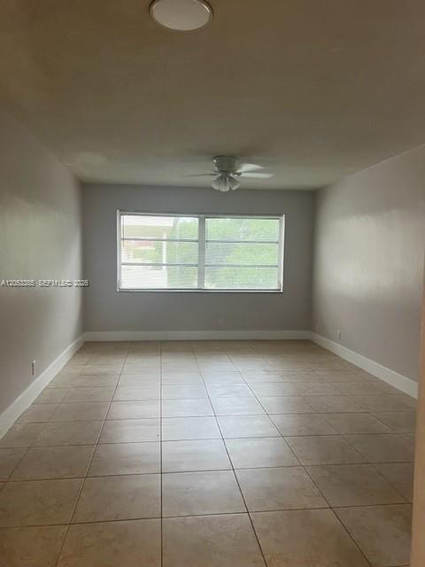 An empty room with light-colored tile flooring, a ceiling fan, and a large window — 4165 SW 67th Ave # 206B, Davie FL 33314, DAVIE, FL