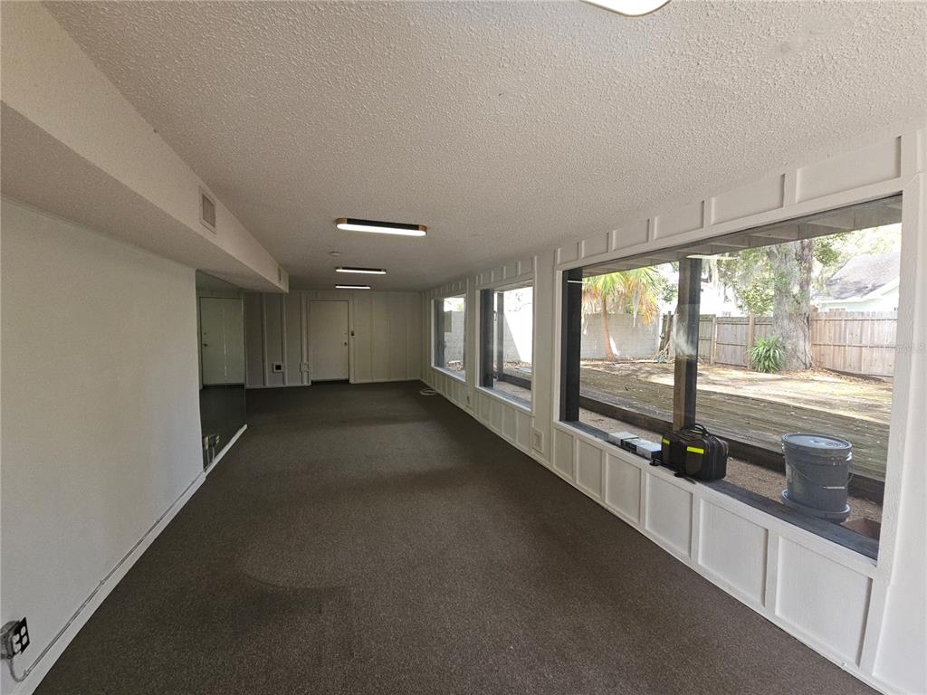A long, carpeted sunroom features large windows overlooking a backyard deck and wooden fence — 529 N FERN CREEK AVENUE, ORLANDO, FL