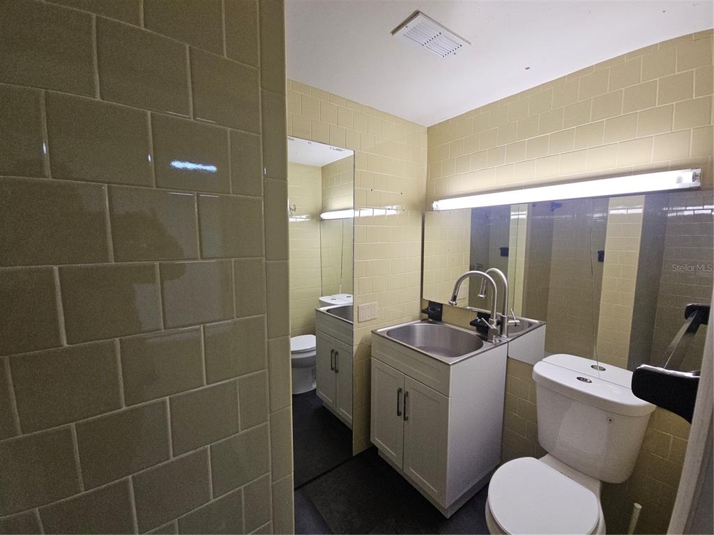 A bathroom features light-colored subway tile walls, a white vanity with a sink, and toilet — 529 N FERN CREEK AVENUE, ORLANDO, FL